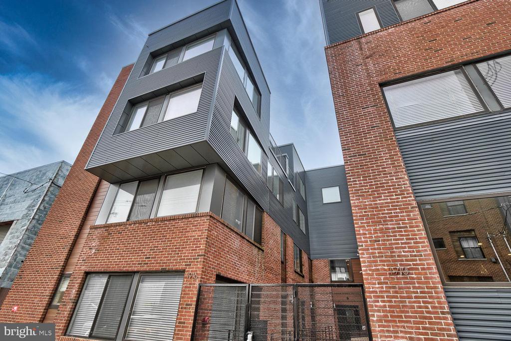 Absolutely gorgeous 2 year old condo within a gated community in the city's hottest neighborhood! Located on a great block surrounded by new construction communities and even more to come! TAX ABATEMENT with 7+ years remaining! 10ft+ ceilings throughout! Enter the front door into the masterfully designed kitchen with high quality quartz countertops and stainless steel appliances. The breakfast bar looks out into the expansive living room with large windows that allow the sunlight to pour in and illuminate the hardwood floors. A perfect room for entertaining company! Storage is no problem here, this main level features a deep closet tucked under the stairs as well as an oversized laundry room with side by side washer/dryer. Head up the stairs to the upper level that showcases two spacious bedrooms along with 2 full bathrooms with beautiful modern tile work and fixtures. Heading up one more level will take you to the private roofdeck where you can enjoy your own slice of the growing Philadelphia Skyline. Take in the fireworks this summer while relaxing on your own roof top oasis! Get in to see this condo today, it will not last long!